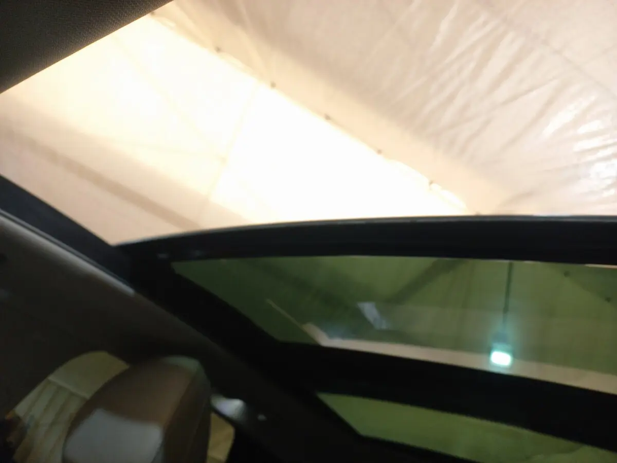 Vue intérieure du toit ouvrant en verre inclinable du Hyundai Tucson gris foncé 2023, version hybride rechargeable.