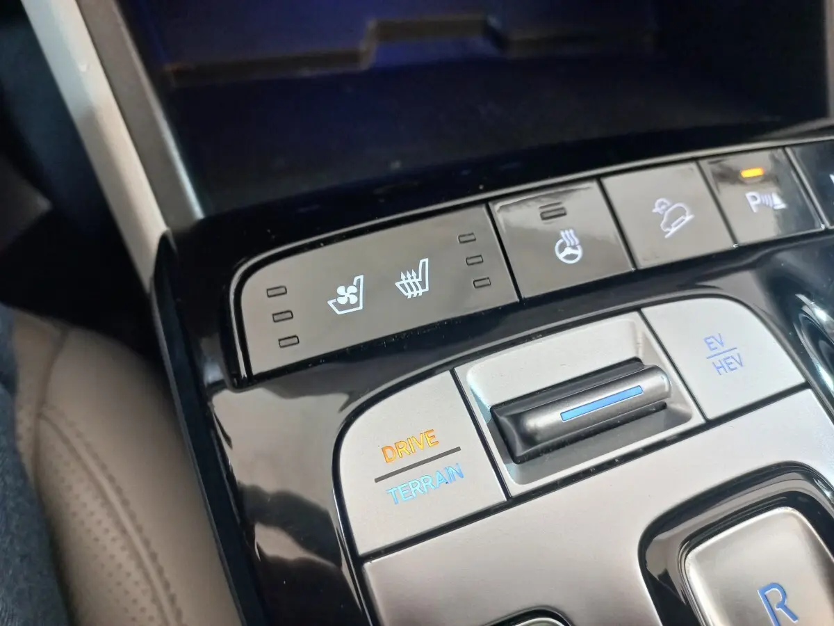 Vue rapprochée du panneau de commandes central gris et noir du Hyundai Tucson 2023 avec boutons de réglage de conduite et sièges chauffants/ventilés.