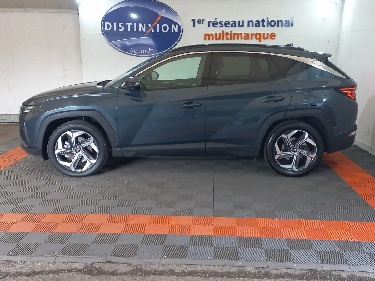 Vue latérale gauche d'un Hyundai Tucson gris foncé 2023, soulignant ses jantes alliage et lignes modernes.