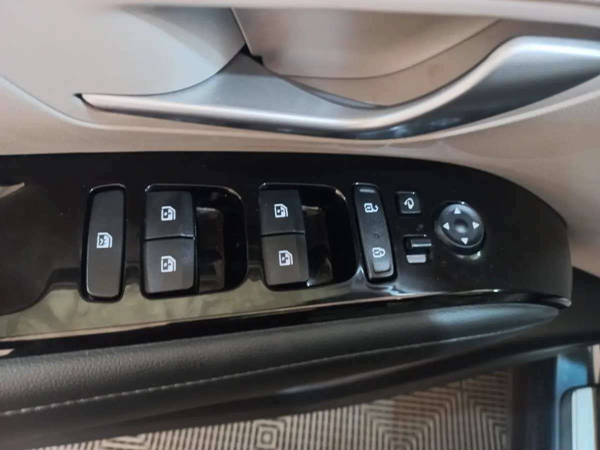 Gros plan sur les commandes de lève-vitres et rétroviseurs côté conducteur du Hyundai Tucson gris foncé 2023.
