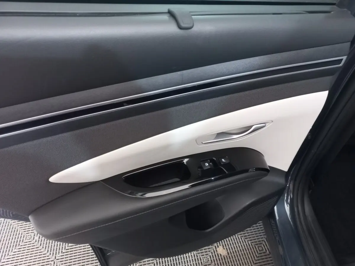 Vue rapprochée de la porte avant droite du Hyundai Tucson gris foncé, avec garniture intérieure bicolore noire et blanche.