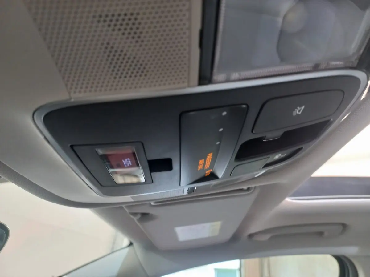 Plafonnier intérieur avec commandes et affichage orange, toit ouvrant partiellement visible d’un Hyundai Tucson gris foncé 2023.