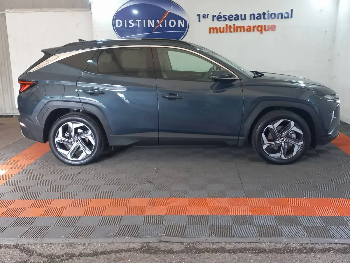 Vue latérale droite du Hyundai Tucson 1.6 PHEV gris foncé, avec jantes alliage et vitres teintées, en intérieur showroom.