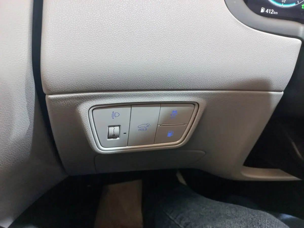 Détail des commandes de réglage des phares et fonctions de maintien sur tableau de bord gris clair du Hyundai Tucson 2023.