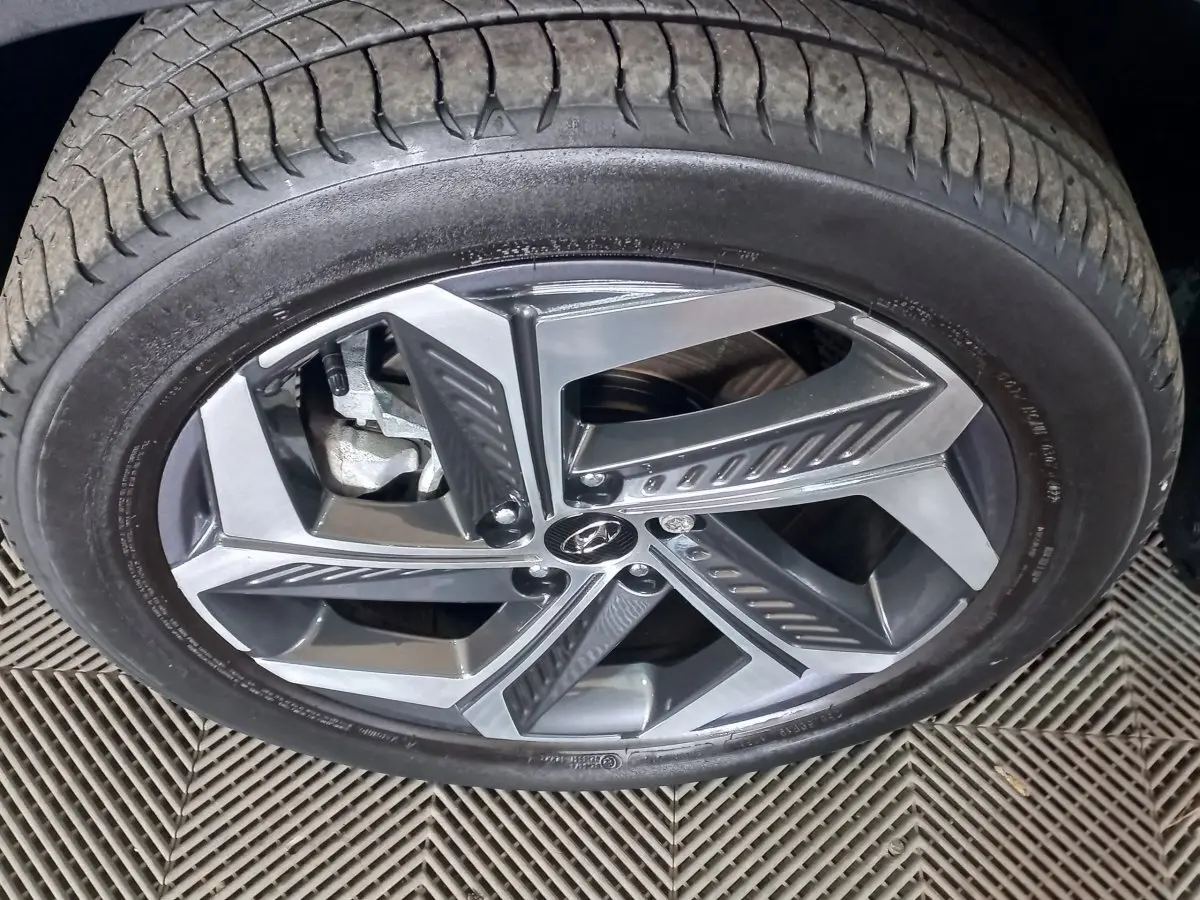 Gros plan sur la roue avant droite du Hyundai Tucson 2023 gris foncé avec jante alliage à cinq branches doubles.