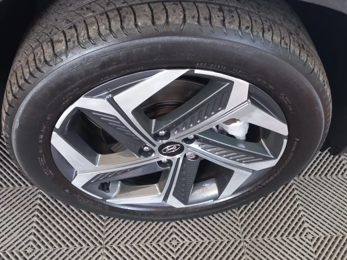 Gros plan sur la roue avant gauche du Hyundai Tucson gris foncé, mettant en valeur la jante alliage au design moderne.