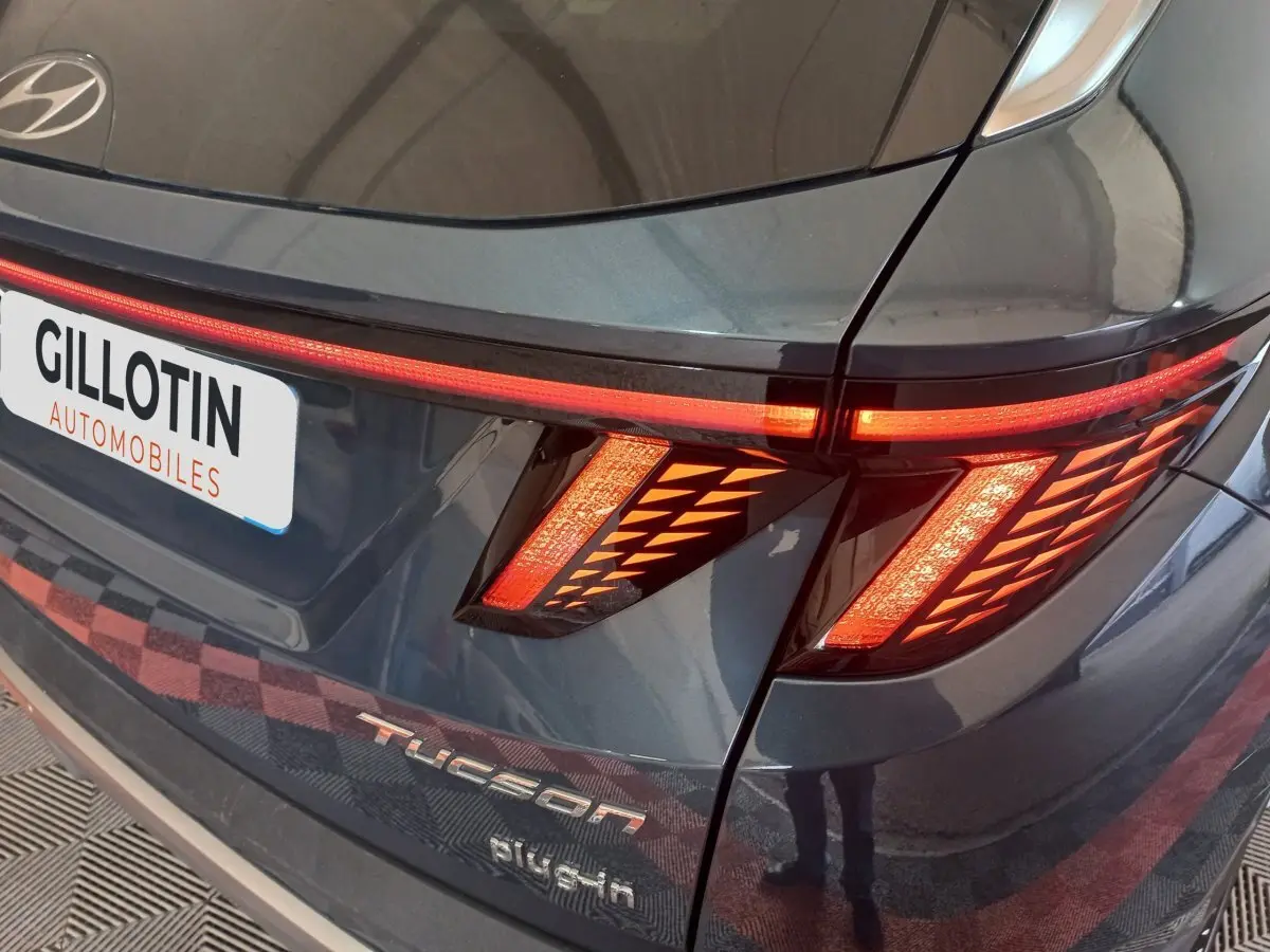 Gros plan arrière droit du Hyundai Tucson gris foncé avec feux LED allumés et logo Tucson visible.
