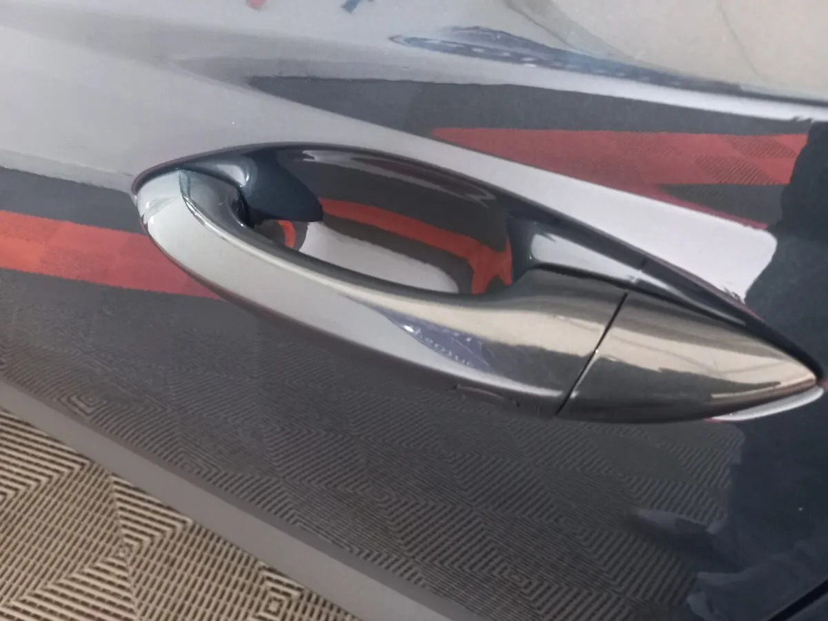 Poignée de porte avant droite gris foncé du Hyundai Tucson 2023 hybride rechargeable vue en gros plan.