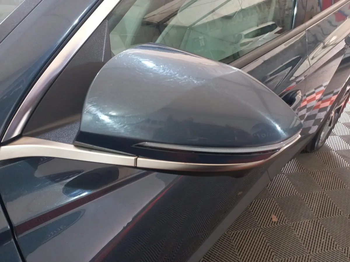 Rétroviseur côté gauche gris foncé du Hyundai Tucson 2023, avec clignotant intégré et carrosserie visible en arrière-plan.