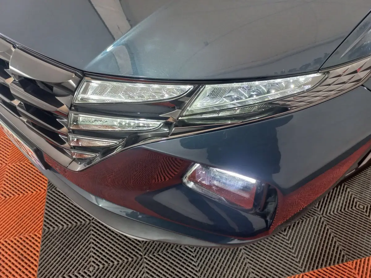 Gros plan sur l'avant droit gris foncé du Hyundai Tucson 2023, mettant en valeur les phares LED et la calandre chromée.