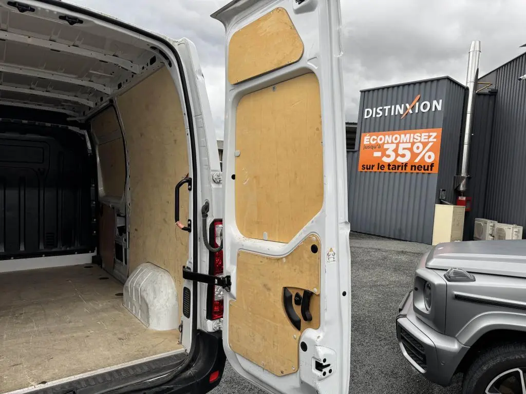 Vue arrière ouverte du Renault Master blanc montrant l'intérieur de la zone de chargement avec habillage bois et porte arrière tôlée.