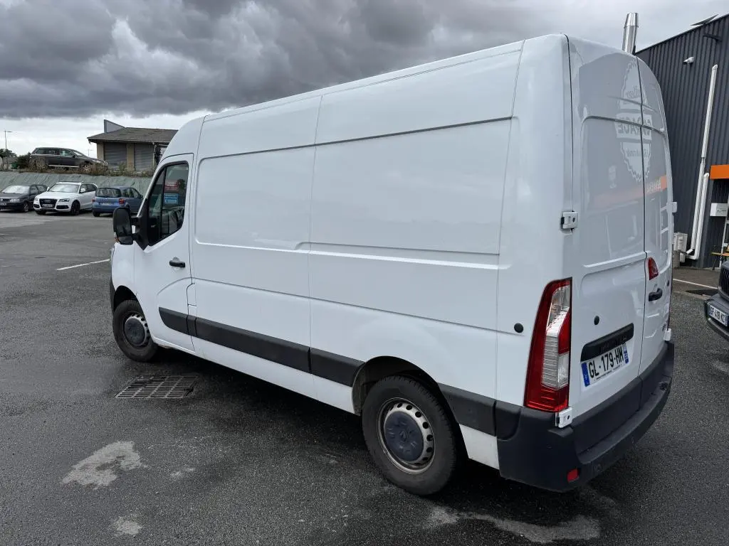 Renault Master blanc en vue 3/4 arrière droit, fourgon utilitaire avec portes arrière tôlées ouvertes à 180° et baguettes latérales noires.