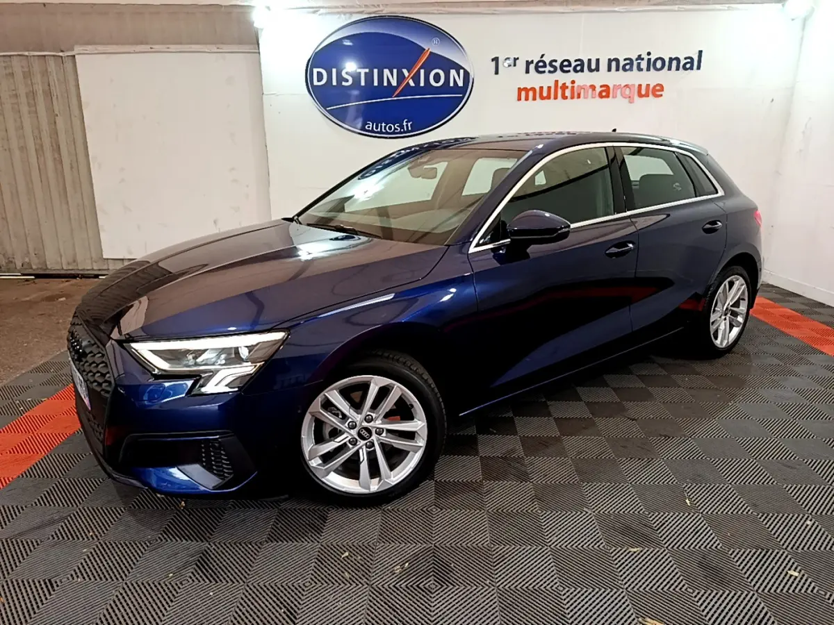 Audi A3 bleu 3/4 avant droit dans un showroom avec jantes alliage et phares LED allumés.