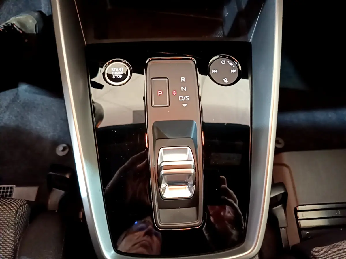 Gros plan sur la console centrale noire brillante de l'Audi A3 35 TFSI 2023 avec levier de vitesses et bouton start/stop.