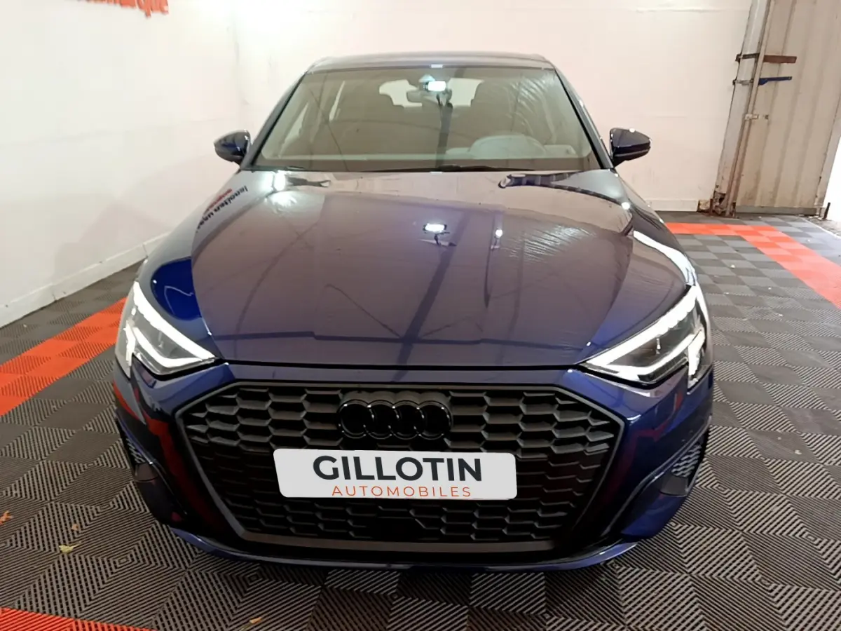 Vue avant d'une Audi A3 35 TFSI bleu nuit avec calandre noire et phares LED allumés en intérieur.