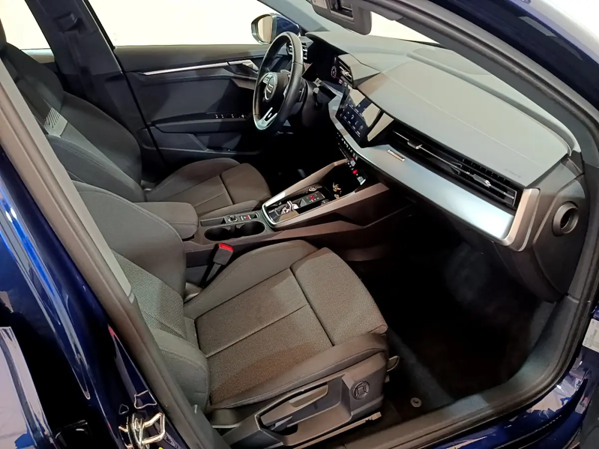 Vue intérieure côté conducteur de l'Audi A3 bleu 2023, avec tableau de bord moderne et sièges tissu gris.