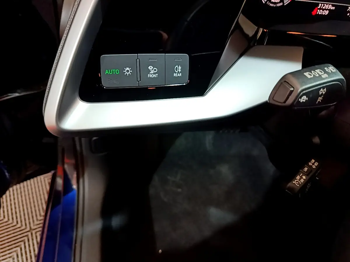 Gros plan sur les commandes d'éclairage et les leviers de la colonne de direction dans l'habitacle d'une Audi A3 bleu 2023.