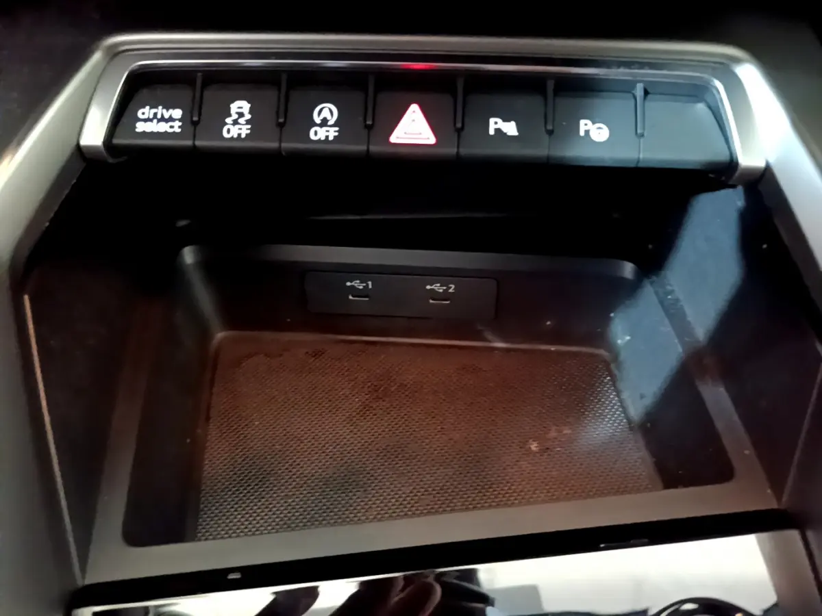 Gros plan sur la console centrale noire de l'Audi A3 35 TFSI 2023 avec boutons de contrôle et ports USB visibles.