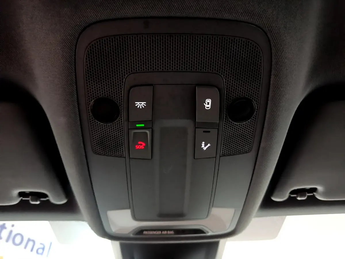 Vue en plongée du panneau de commandes au plafond intérieur de l'Audi A3 bleu 2023 avec bouton SOS rouge et éclairage.