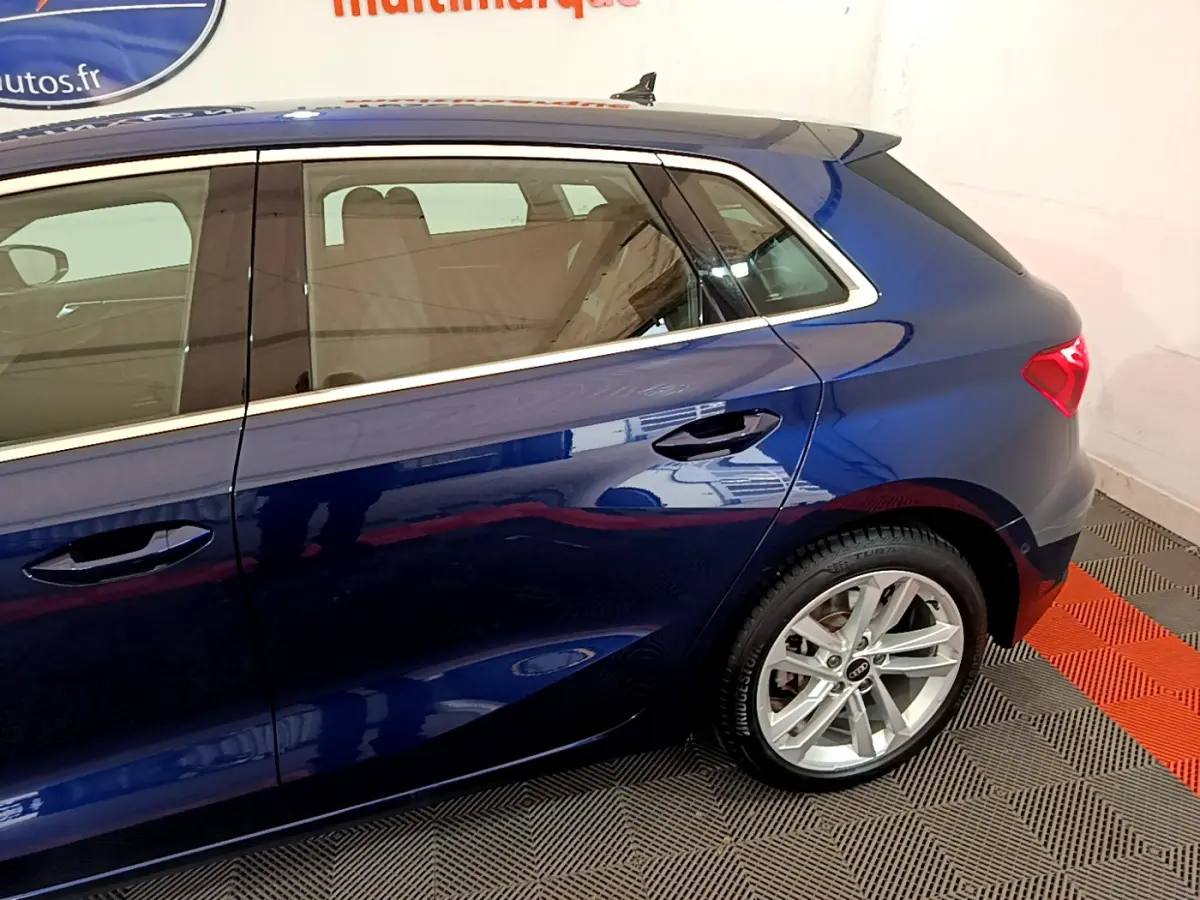 Vue côté droit arrière d'une Audi A3 35 TFSI bleu métallisé avec jante alliage et feux arrière LED.