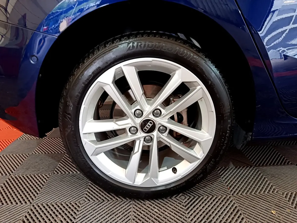 Gros plan sur la roue avant gauche d'une Audi A3 bleu 2023 avec jante alliage argentée à design moderne.