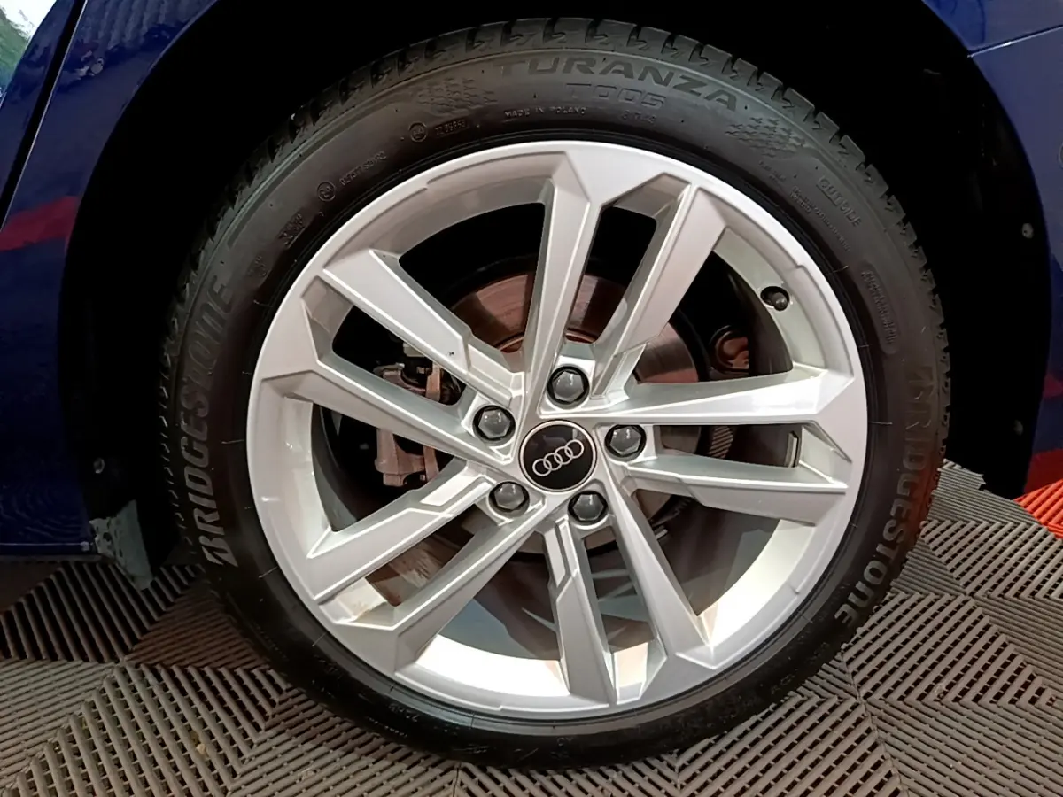 Gros plan sur la roue avant gauche de l'Audi A3 bleu 2023 avec jante alliage et logo Audi au centre.