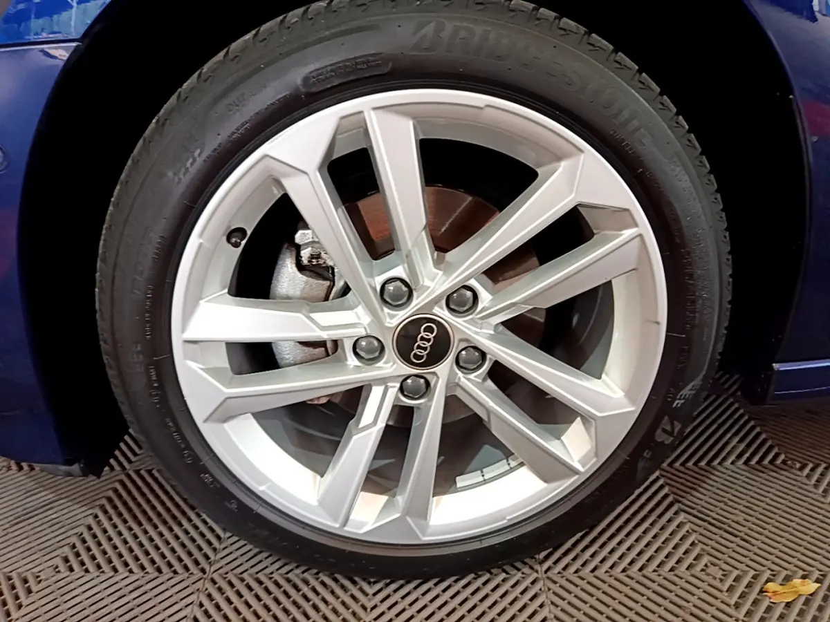 Gros plan sur la roue avant gauche d'une Audi A3 bleu 2023 avec jante alliage argentée à design moderne.