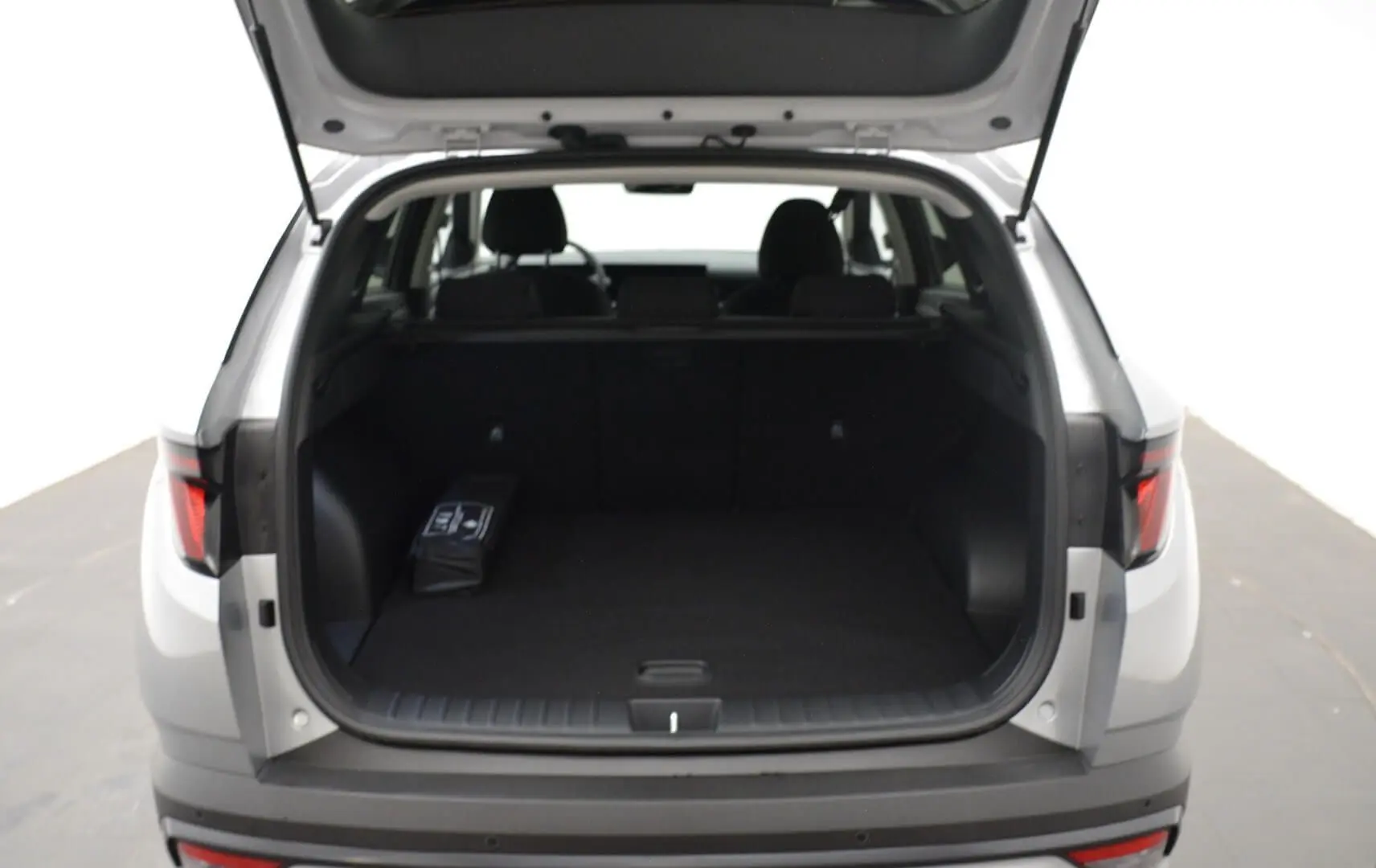 Vue arrière du Hyundai Tucson 2025 Shimmering Silver avec coffre ouvert et intérieur noir visible.