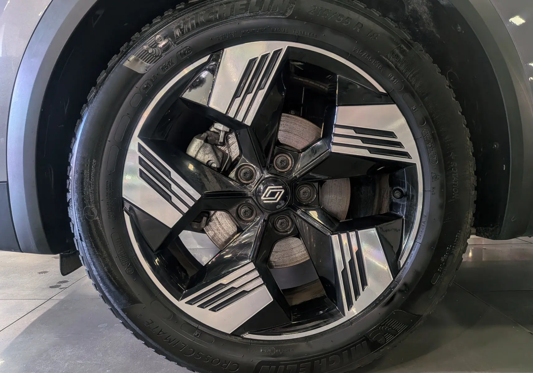 Gros plan sur la jante noire et argentée du Renault Symbioz gris Cassiopé, mettant en valeur le logo central et le pneu Michelin.