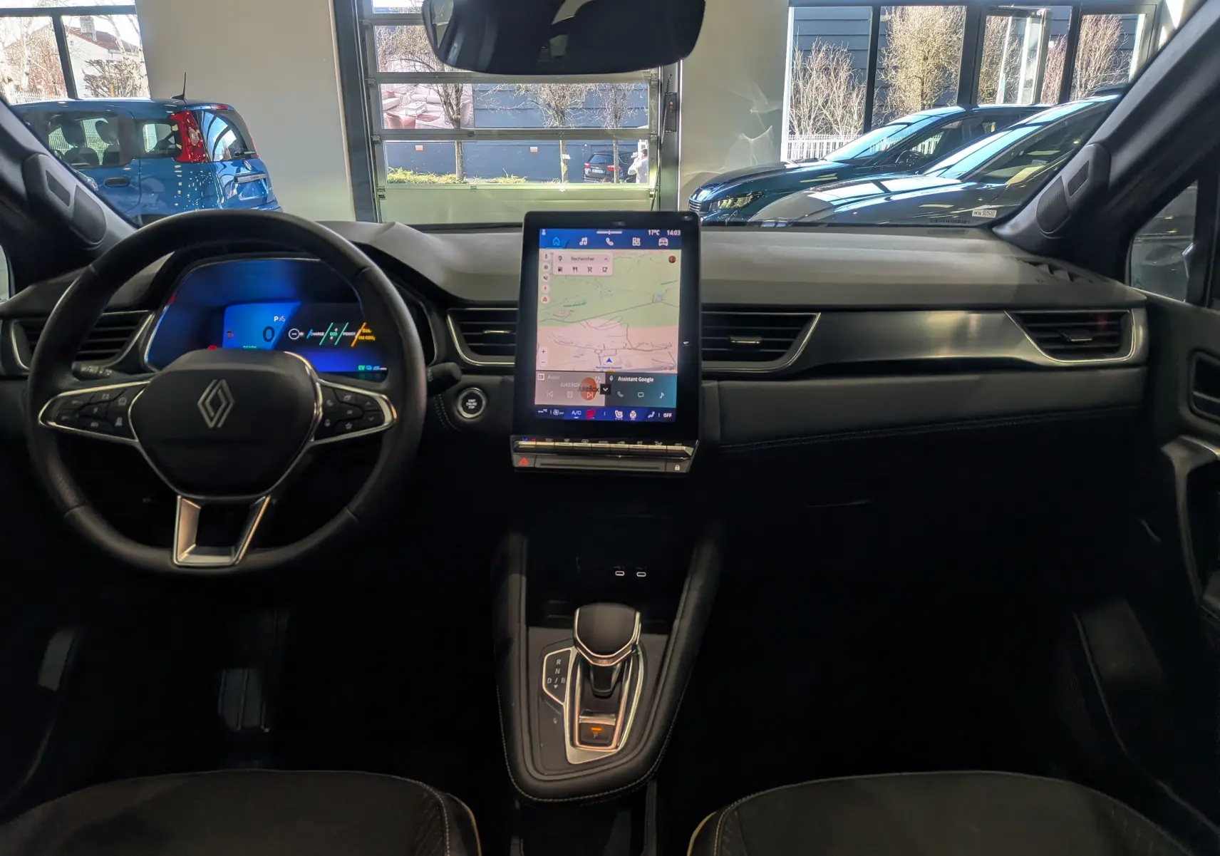 Vue intérieure frontale du tableau de bord du Renault Symbioz E-TECH gris, avec écran tactile vertical et volant multifonction.