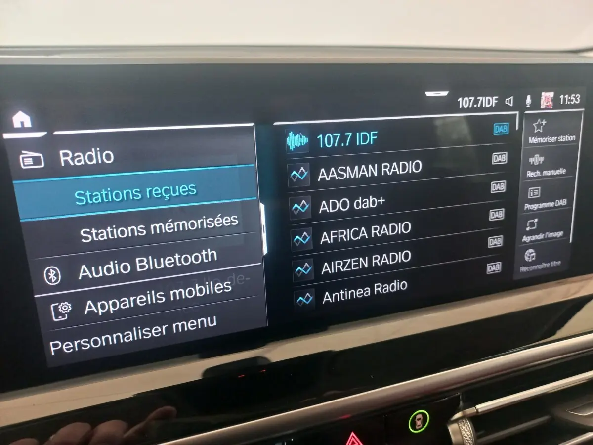 Écran tactile central du tableau de bord du BMW X3 xDrive30e 2022 affichant les stations radio DAB.