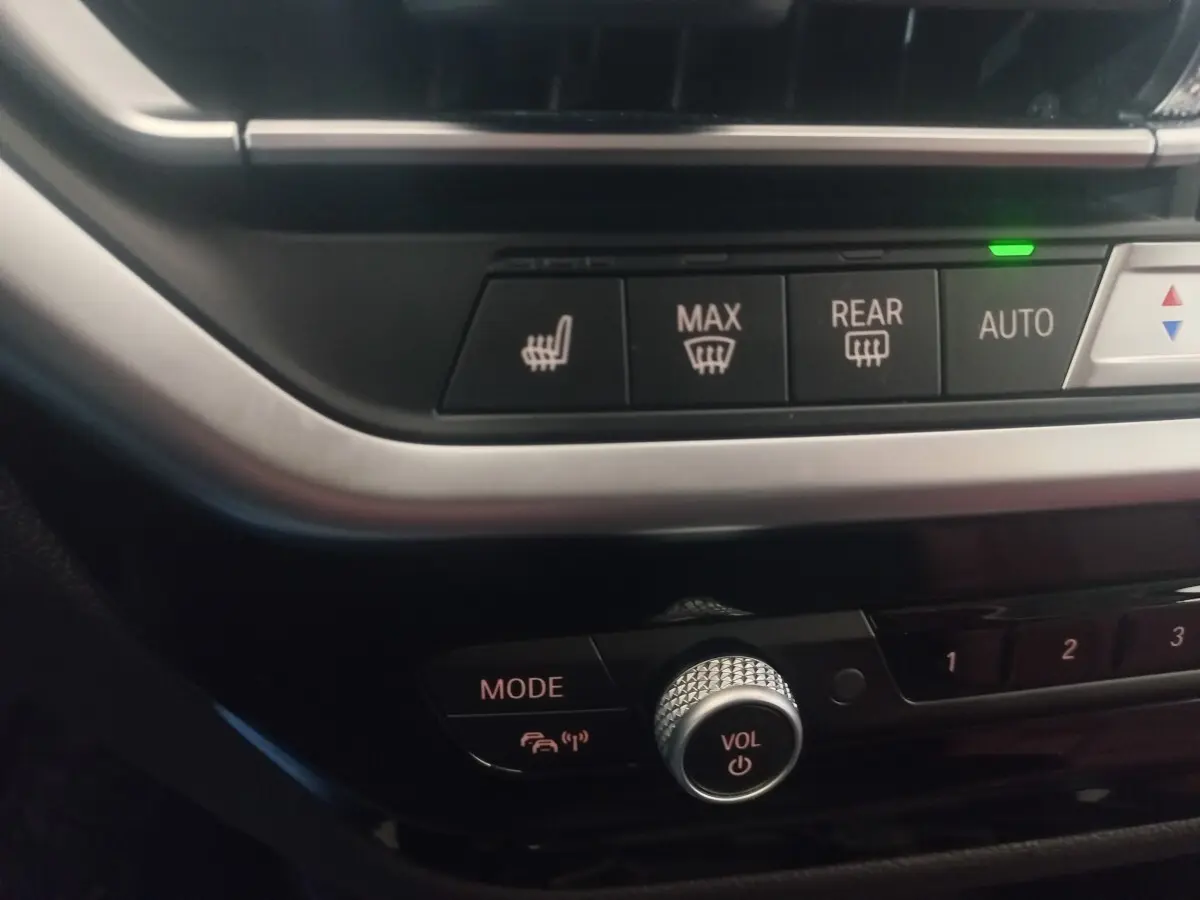 Gros plan sur la console centrale du BMW X3 blanc, montrant les commandes de chauffage et le bouton volume.