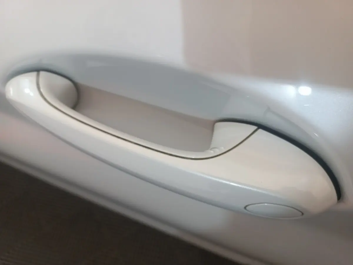 Poignée de porte blanche en gros plan sur BMW X3 xDrive30e 2022, finition Business Design.