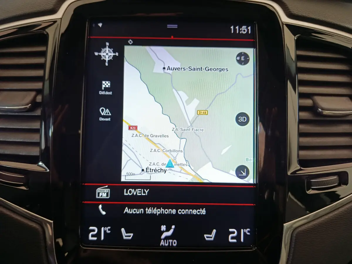 Écran tactile central du tableau de bord du Volvo XC90 gris clair, affichant la navigation GPS et la climatisation à 21°C.