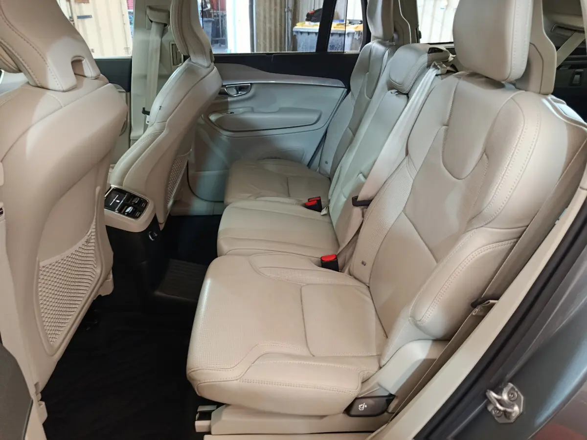 Vue côté droit de la banquette arrière cuir beige du Volvo XC90 gris clair avec appuie-têtes et ceinture de sécurité.
