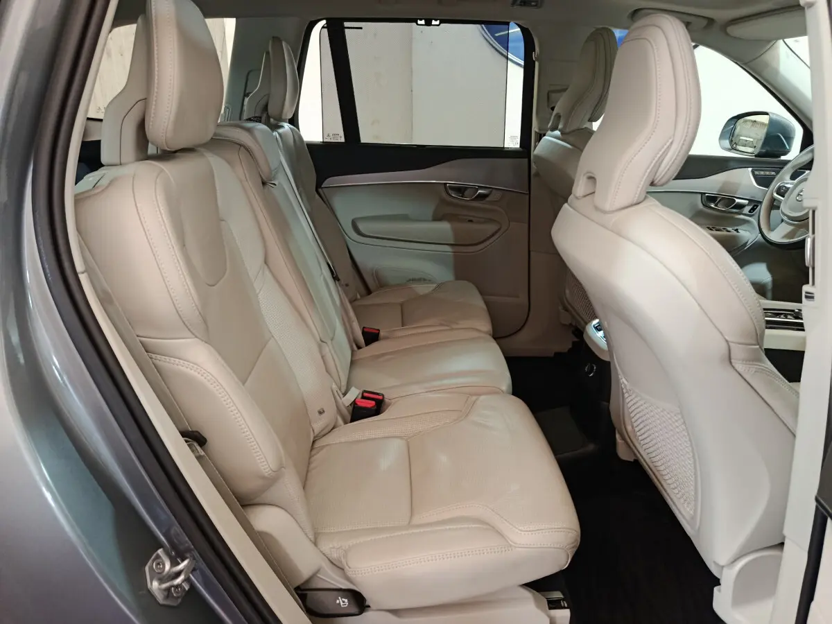 Vue côté gauche sur l'intérieur beige cuir du Volvo XC90 T8 hybride, mettant en valeur les sièges arrière spacieux.