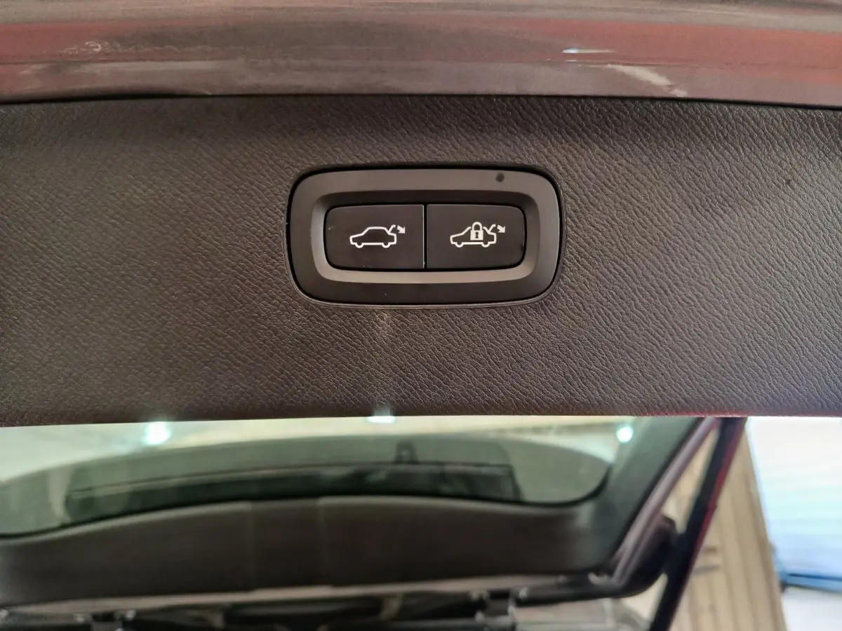 Gros plan sur les boutons d'ouverture et verrouillage électrique du coffre du Volvo XC90 gris clair, vue intérieure du hayon.