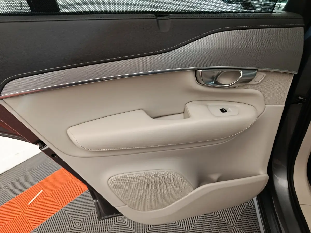 Gros plan sur la porte arrière droite beige et noire du Volvo XC90 T8, avec poignée chrome et commande de vitre.