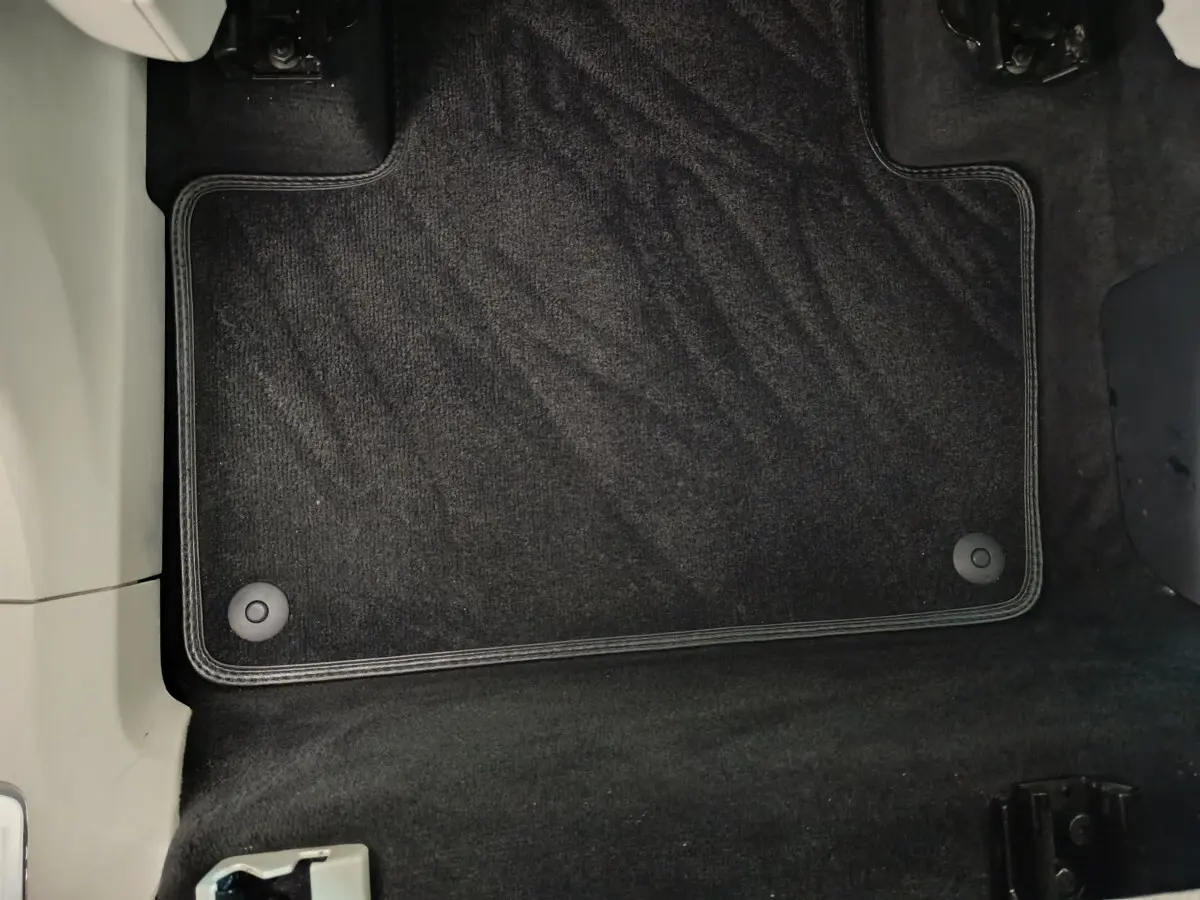 Tapis de sol noir côté conducteur dans l'habitacle d'un Volvo XC90 T8 gris clair, vue rapprochée.