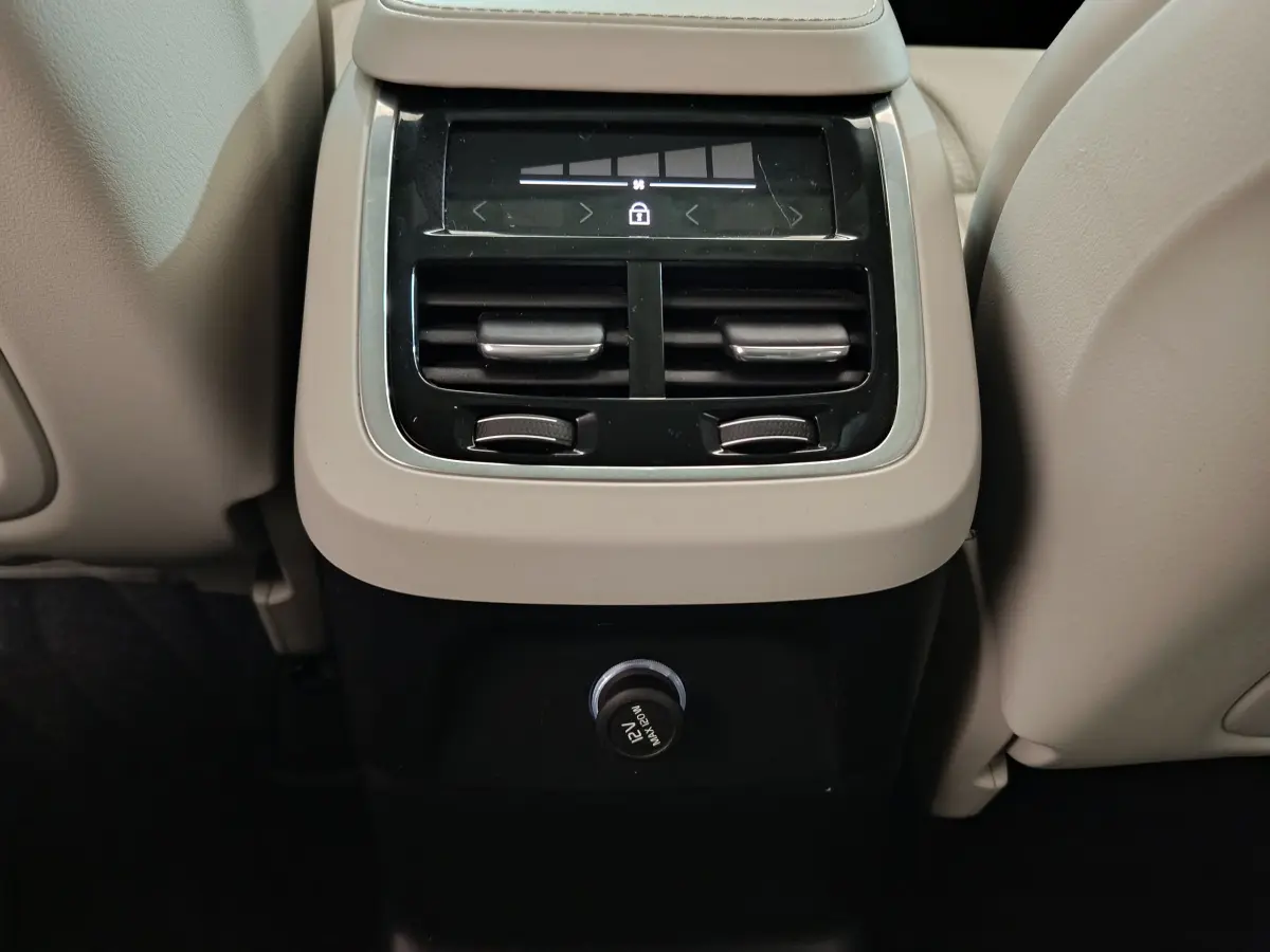 Vue rapprochée de la console arrière beige du Volvo XC90 T8 avec commandes de climatisation et prise 12V.