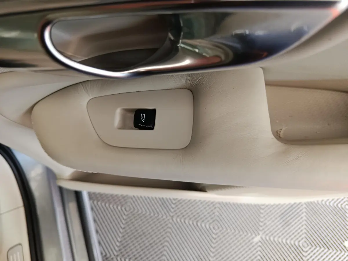 Gros plan sur la commande de lève-vitre beige côté gauche intérieur d'un Volvo XC90 gris clair de 2019.