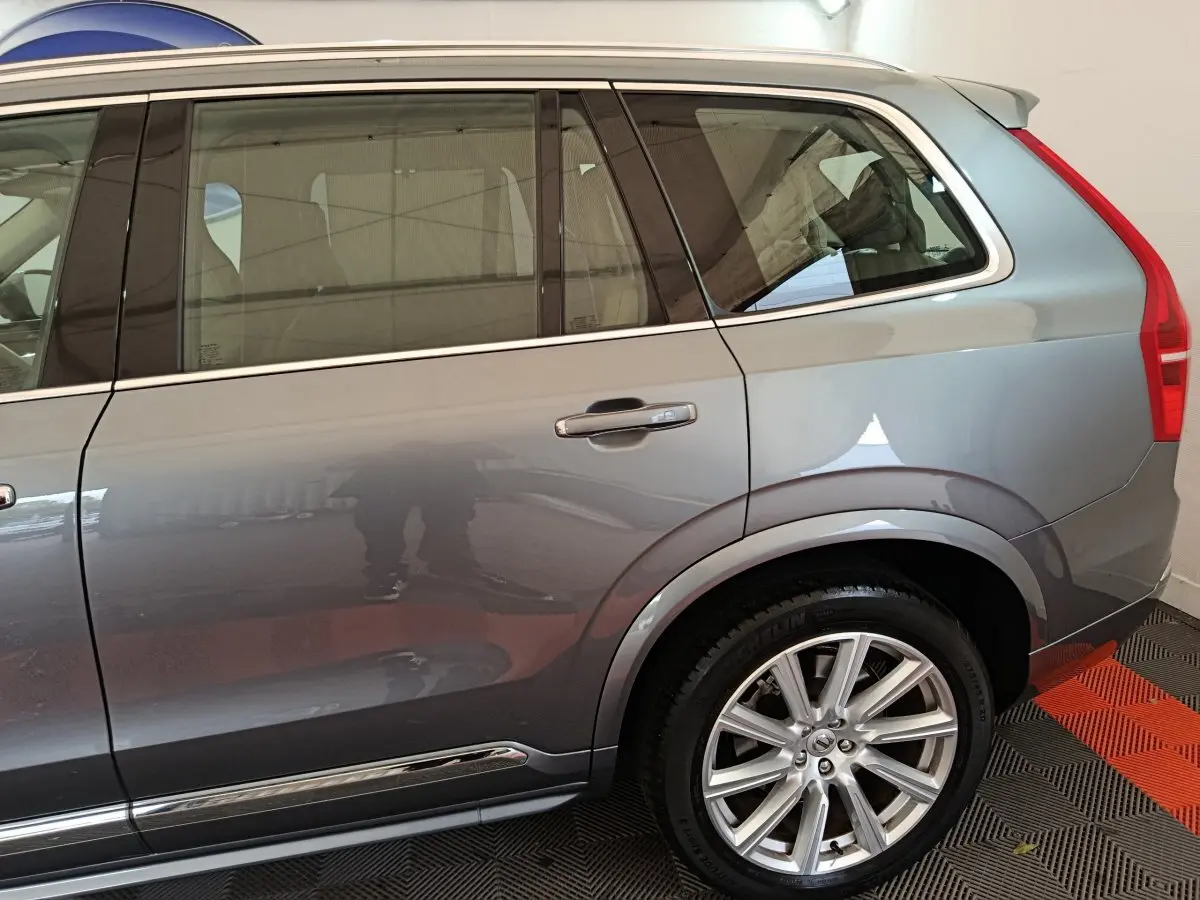 Vue côté droit arrière du Volvo XC90 T8 gris clair, mettant en valeur la roue alliage et les vitres teintées.