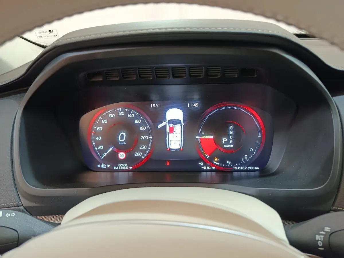 Tableau de bord numérique du Volvo XC90 T8 hybride, affichage vitesse et énergie en rouge et noir, vue frontale rapprochée.