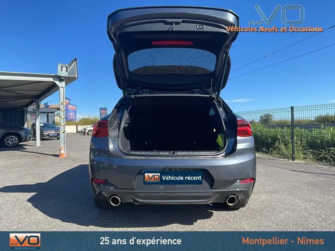 Vue arrière d'un BMW X2 gris 2019 avec coffre ouvert, double sortie d'échappement et jantes alliage 19 pouces visibles.