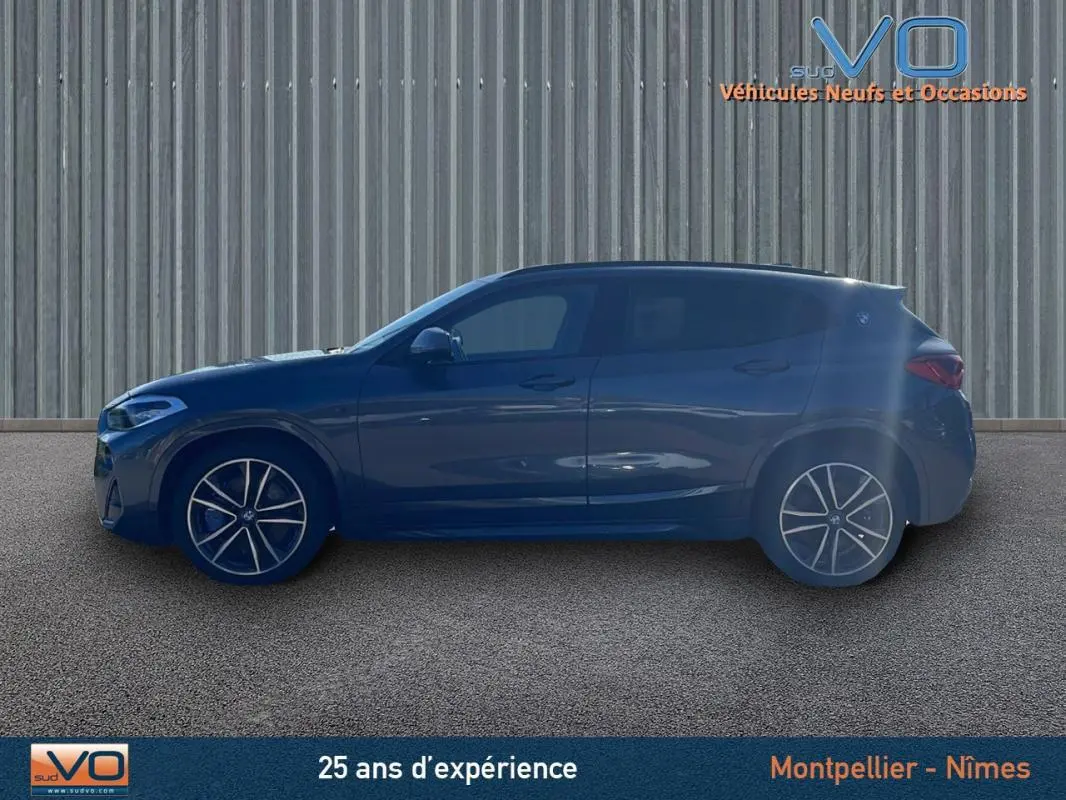 Profil côté gauche d'un BMW X2 F39 M35i gris avec jantes alliage 19 pouces sur fond industriel.