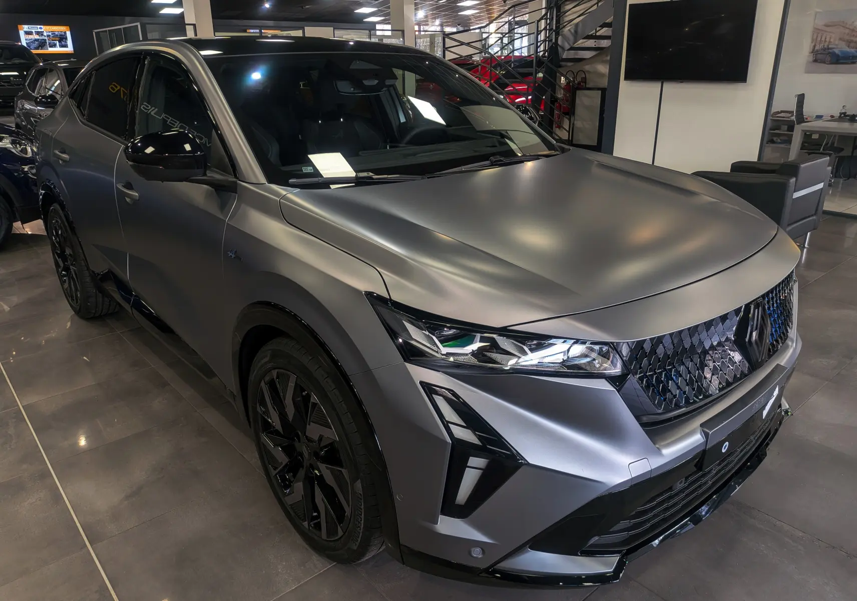 Renault Rafale E-Tech gris schiste satin, vue 3/4 avant droit, calandre noire et phares LED distinctifs.