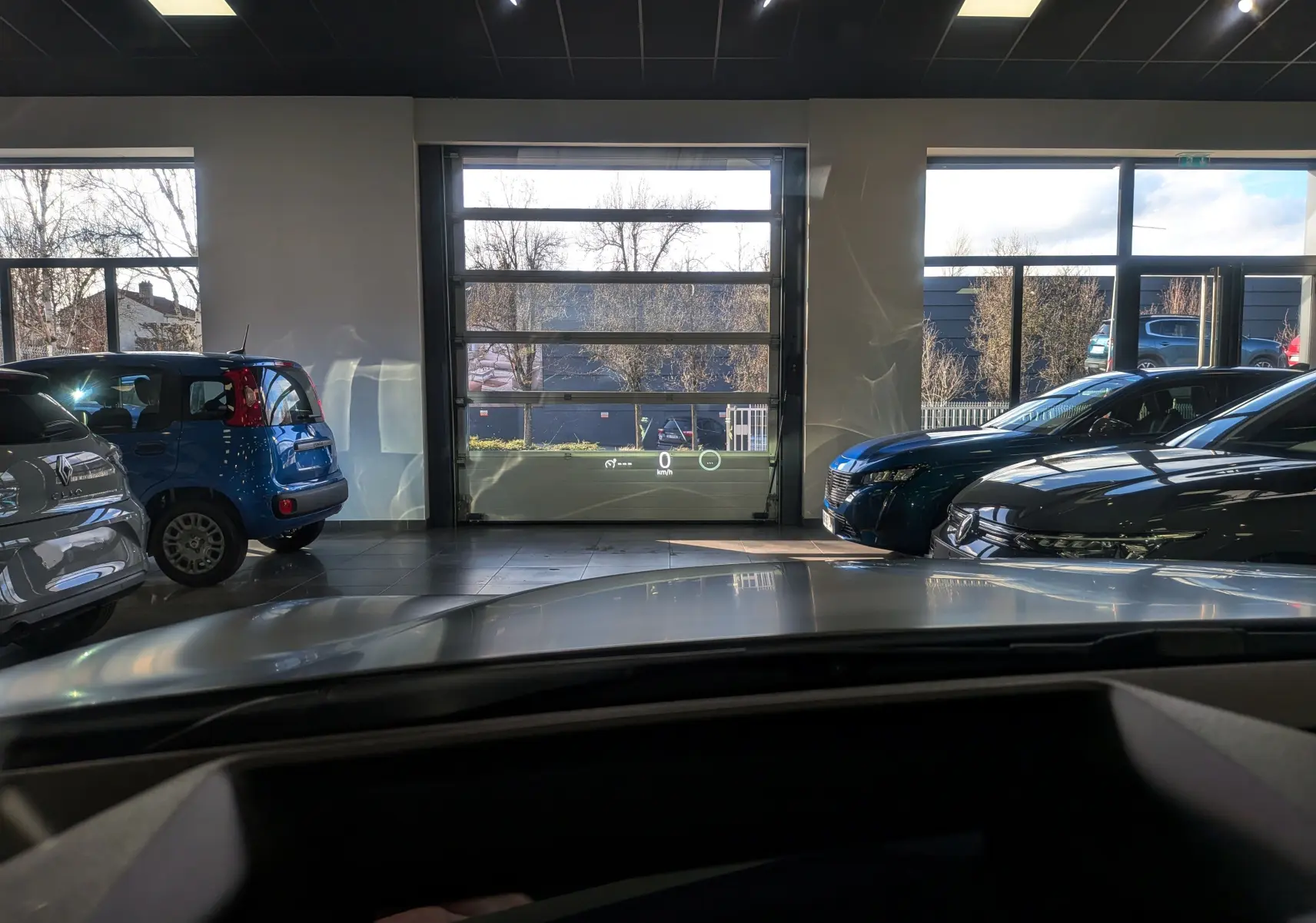 Vue intérieure avant du Renault Rafale E-TECH gris schiste satin, avec affichage tête haute visible dans un showroom lumineux.