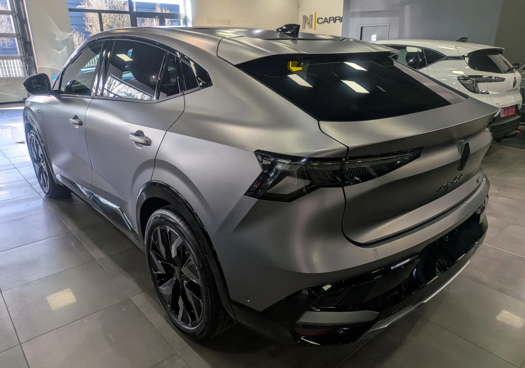 Vue 3/4 arrière droite du Renault Rafale E-TECH gris schiste satin, soulignant ses feux arrière effilés et ses jantes noires.