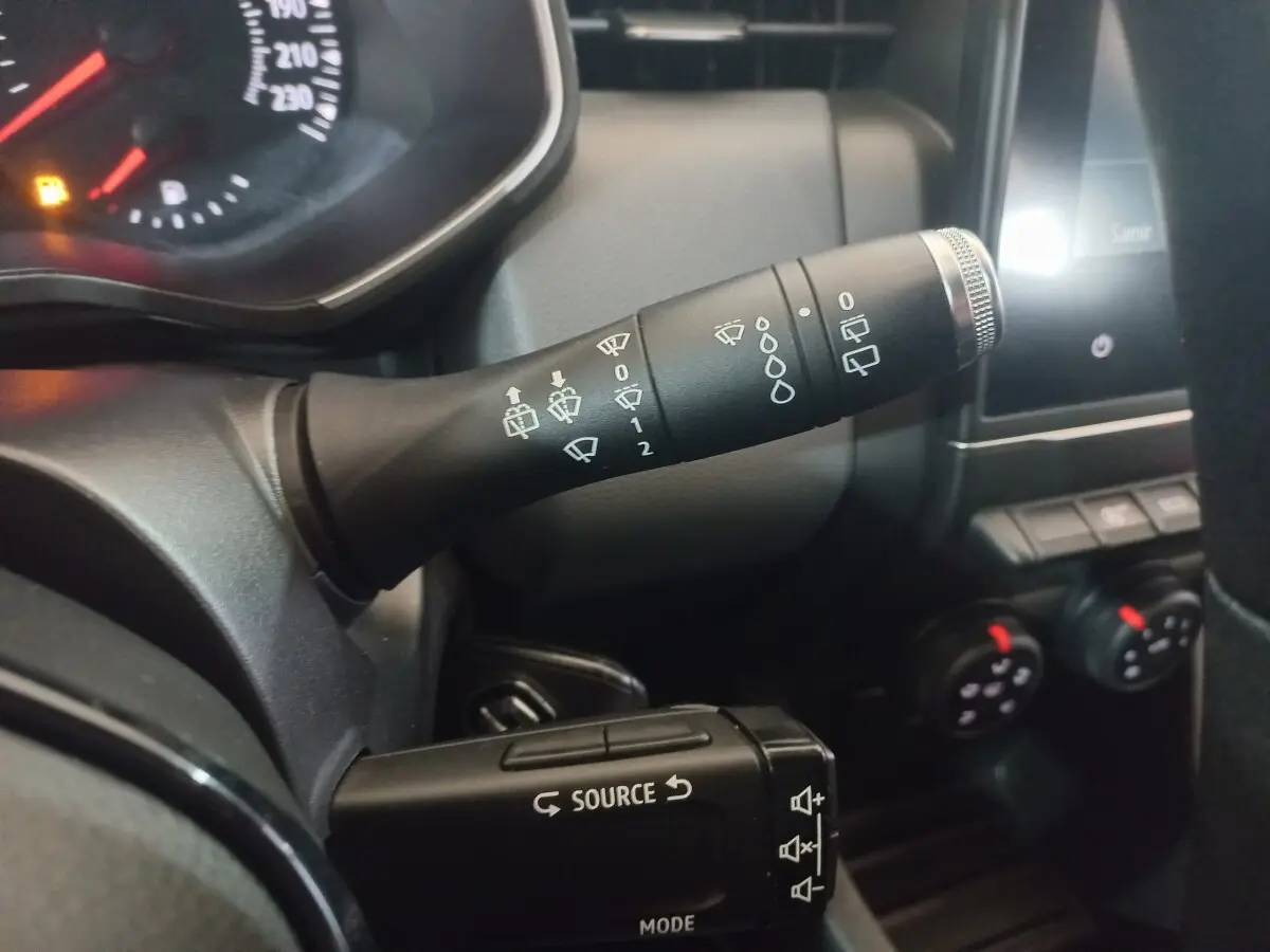 Gros plan intérieur sur la commande d’essuie-glace et les boutons multimédias du tableau de bord d’une Renault Clio blanche 2020.