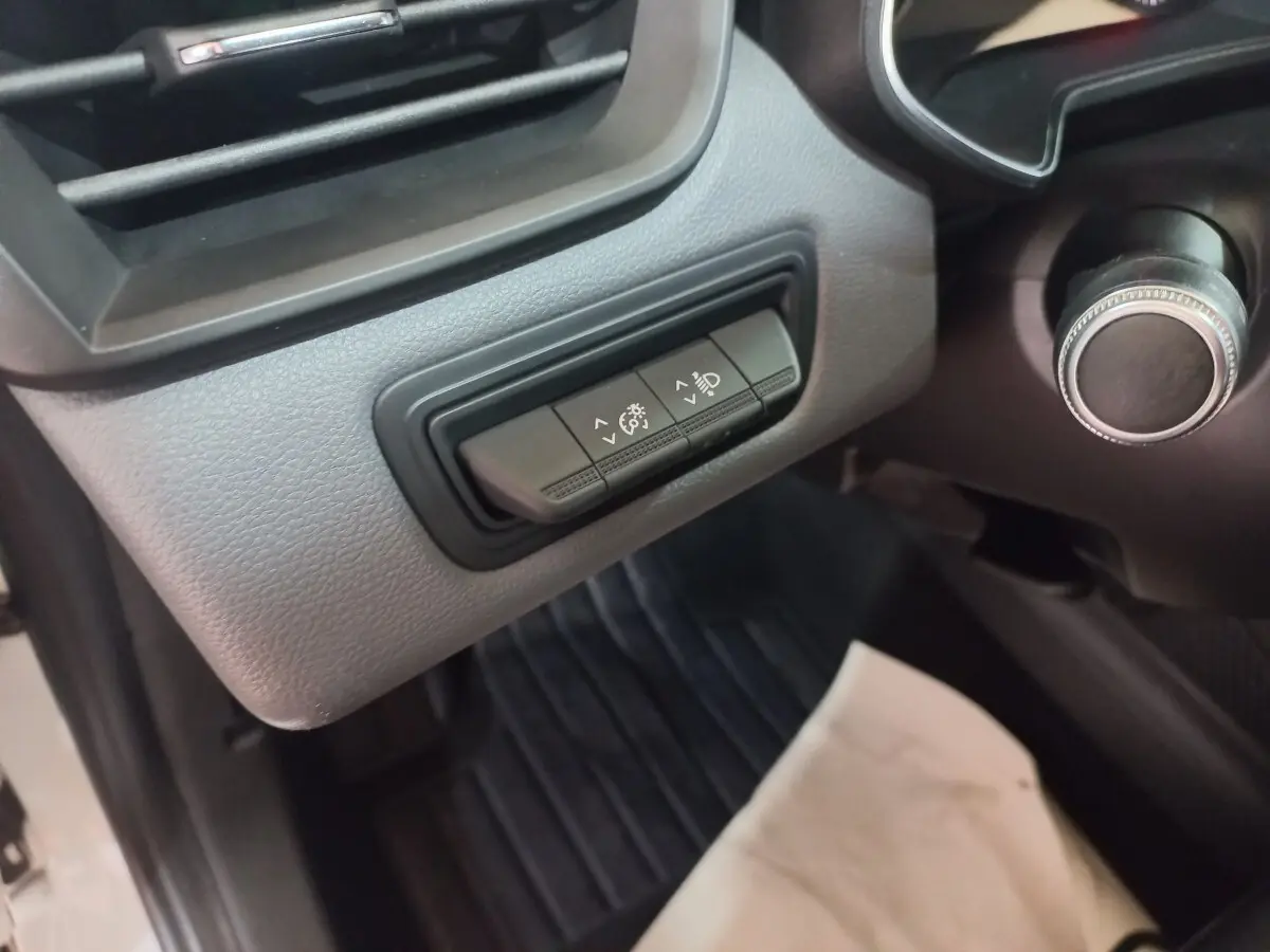 Détail du tableau de bord côté gauche de la Renault Clio blanche 2020, avec commandes de réglage des phares.